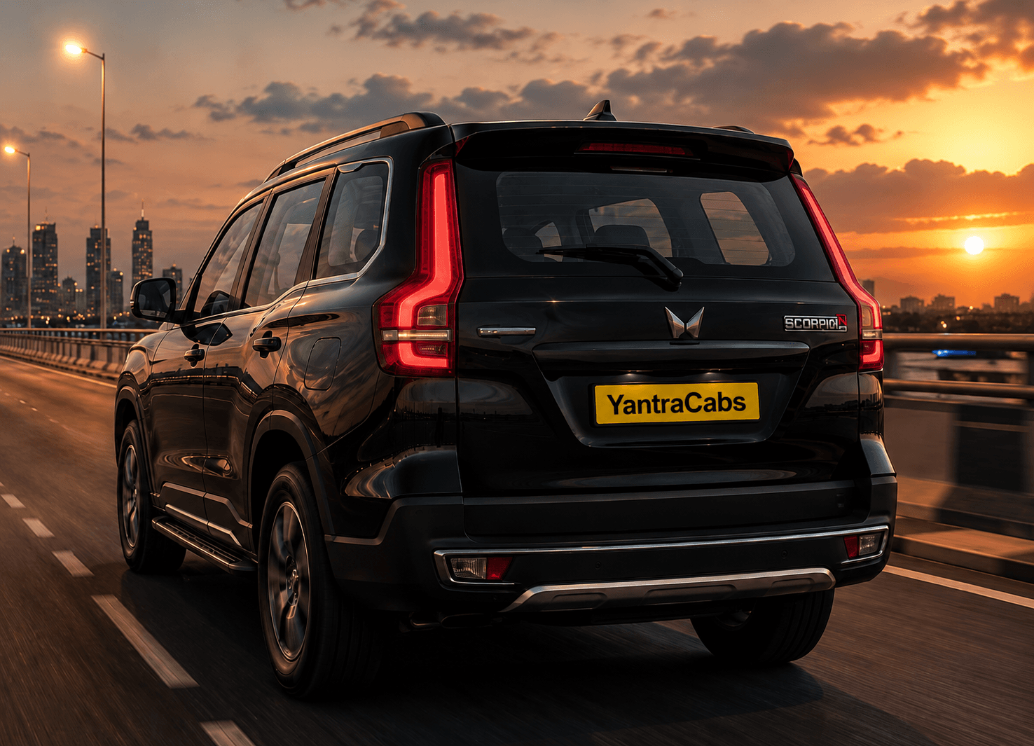 A YantraCabs Mahindra Scorpio N on a highway at sunset